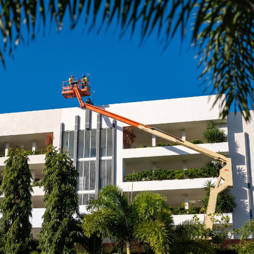 commer-500-2 Two commercial painters working from an elevated platform on the exterior of a high-rise building.